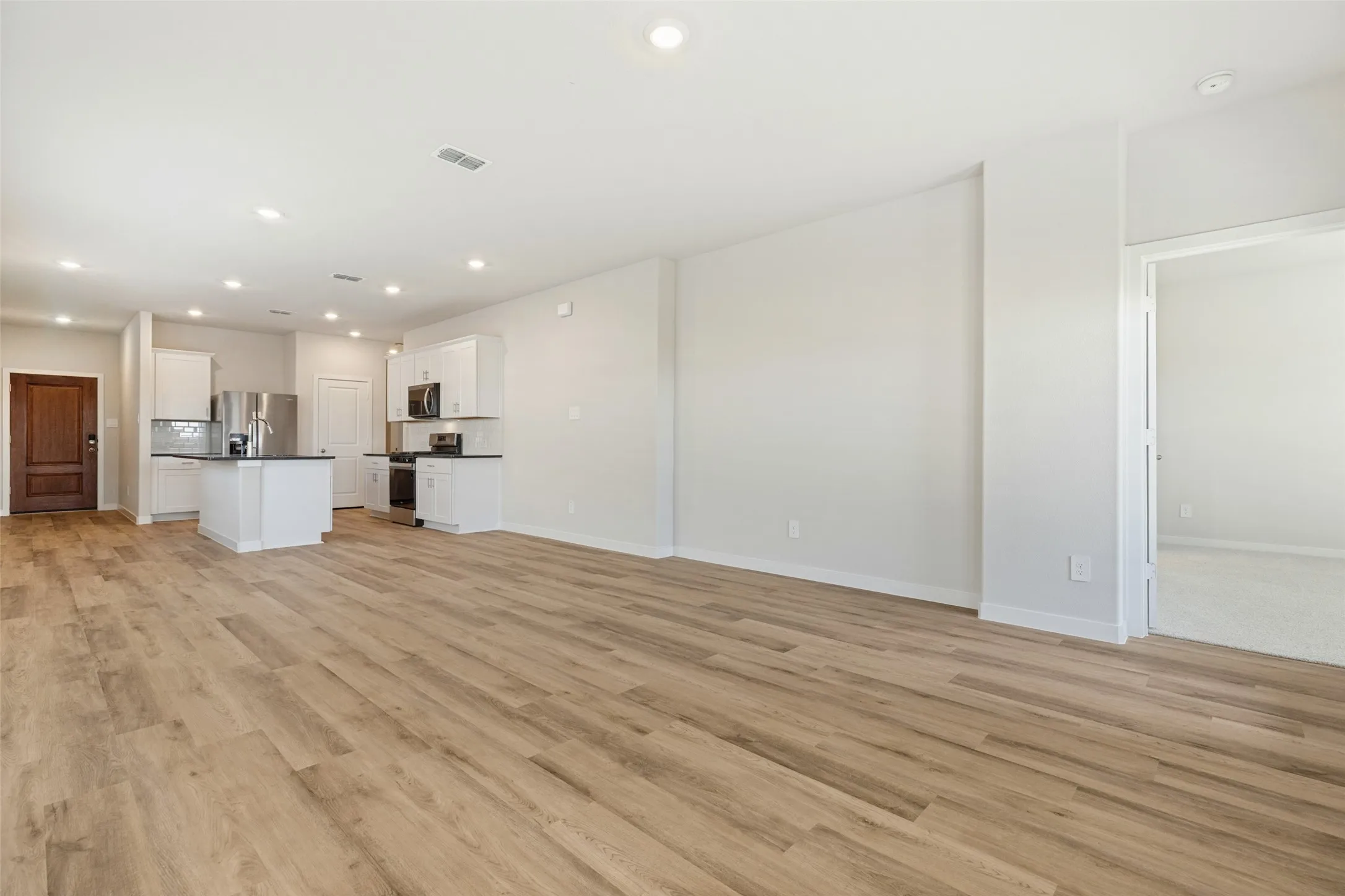 One Seamless Living Space! - Enjoy the convenience of an open-concept floor plan that brings together the family room, dining area, and kitchen. Continuous executive vinyl plank flooring and recessed lighting create a cohesive, inviting atmosphere throughout.