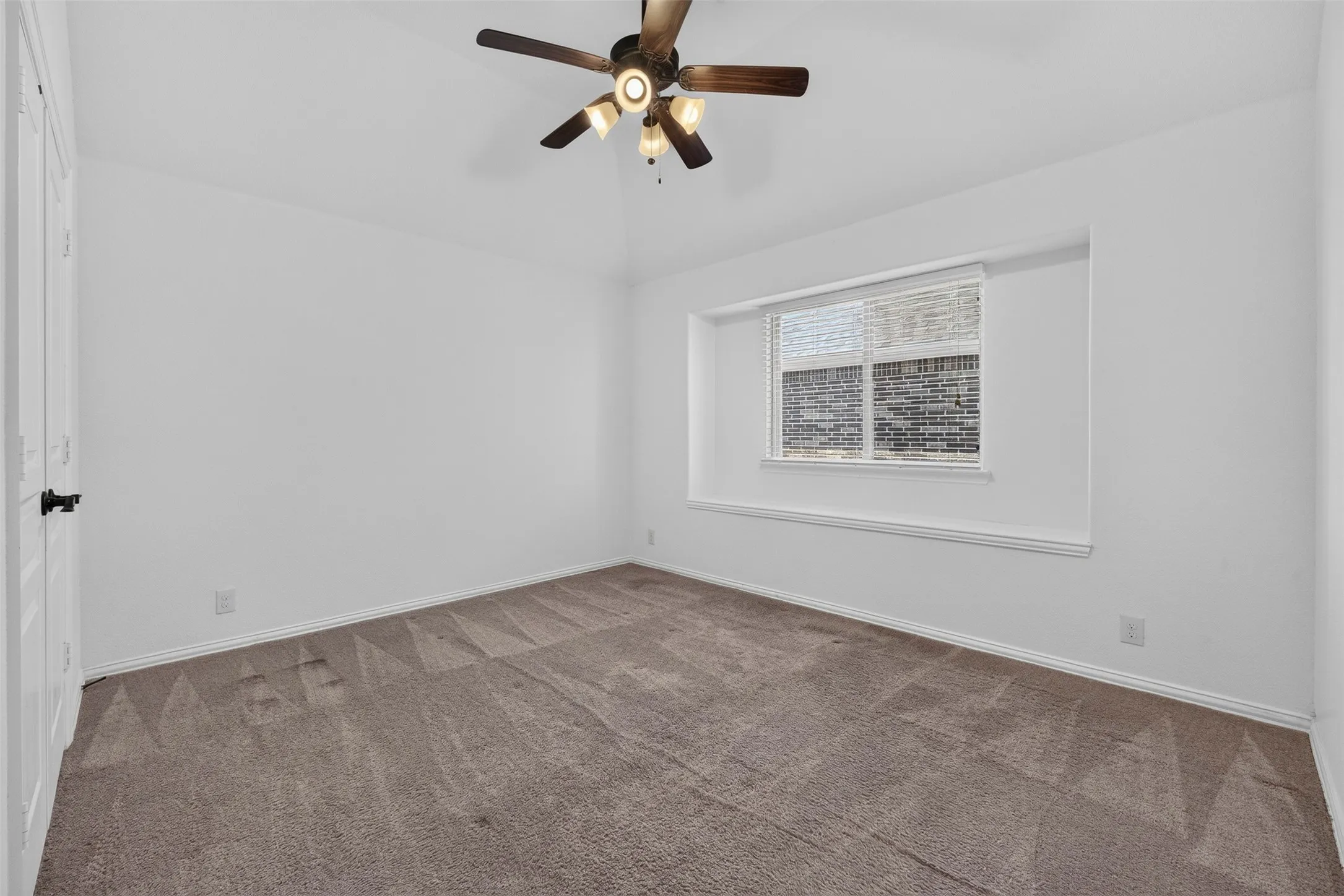 Vaulted ceiling featuring a ceiling fan with light fixture, neutral carpet flooring, and a window with blinds