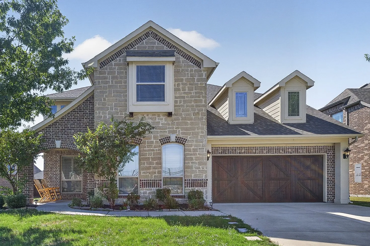Two-story home featuring a brick and stone exterior with multiple gabled rooflines and dormer windows