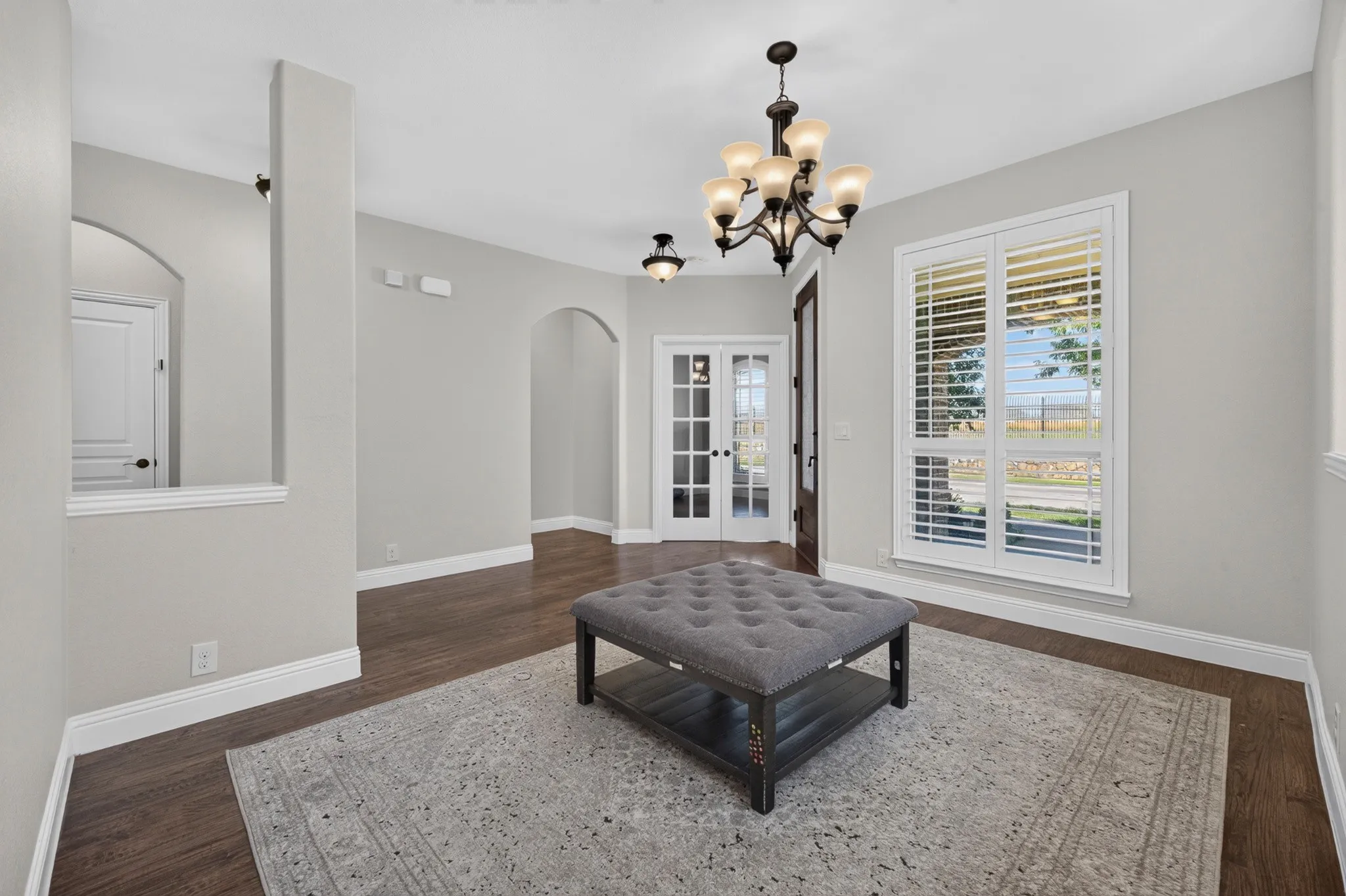 Elegant foyer showcasing soaring ceilings, dark wood-finish flooring, and a decorative chandelier