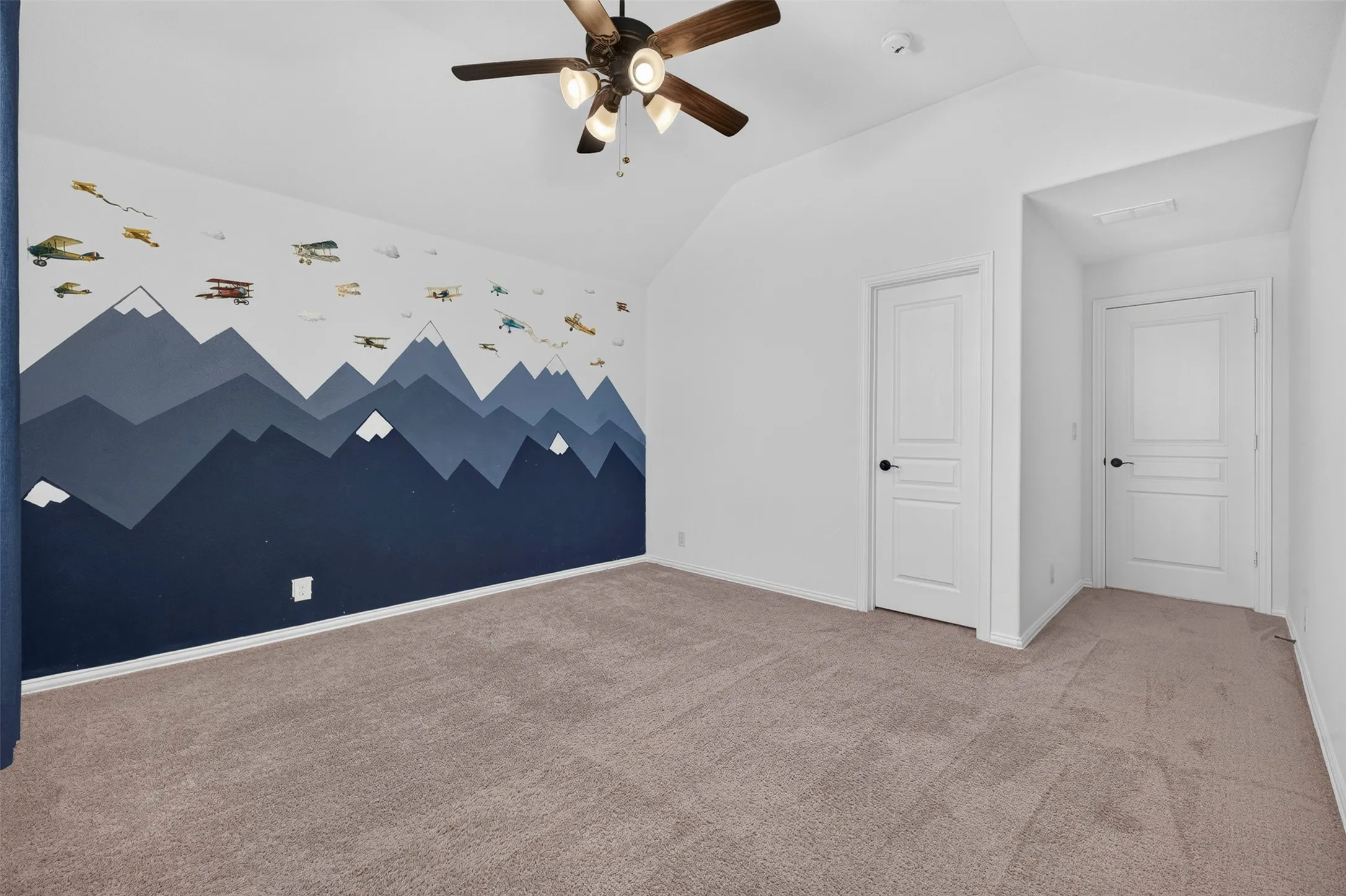 Vaulted ceiling, ceiling fan, neutral carpeting, white interior doors, and white painted walls