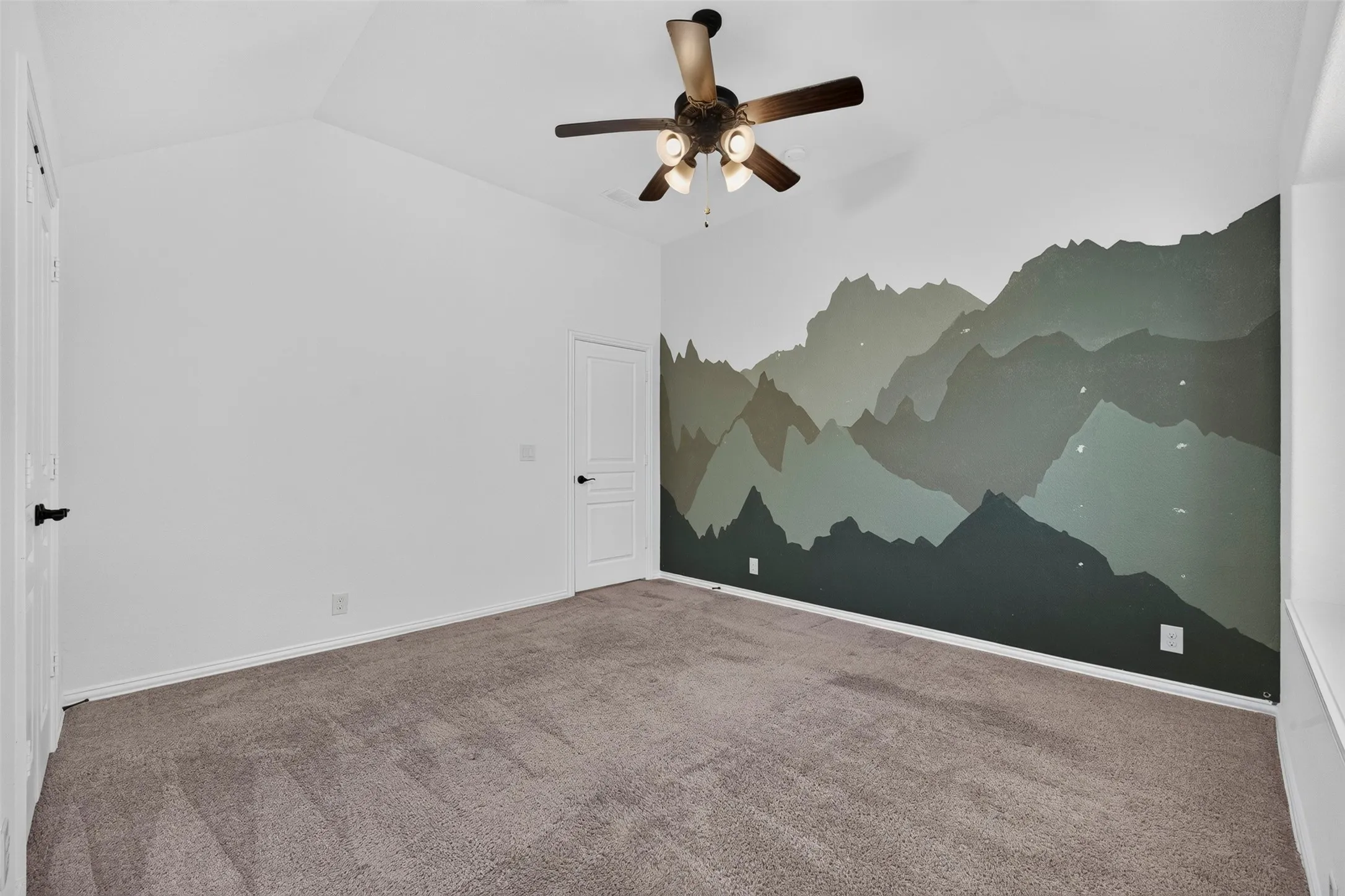 Vaulted ceiling featuring a ceiling fan, carpet flooring, and a wall mural