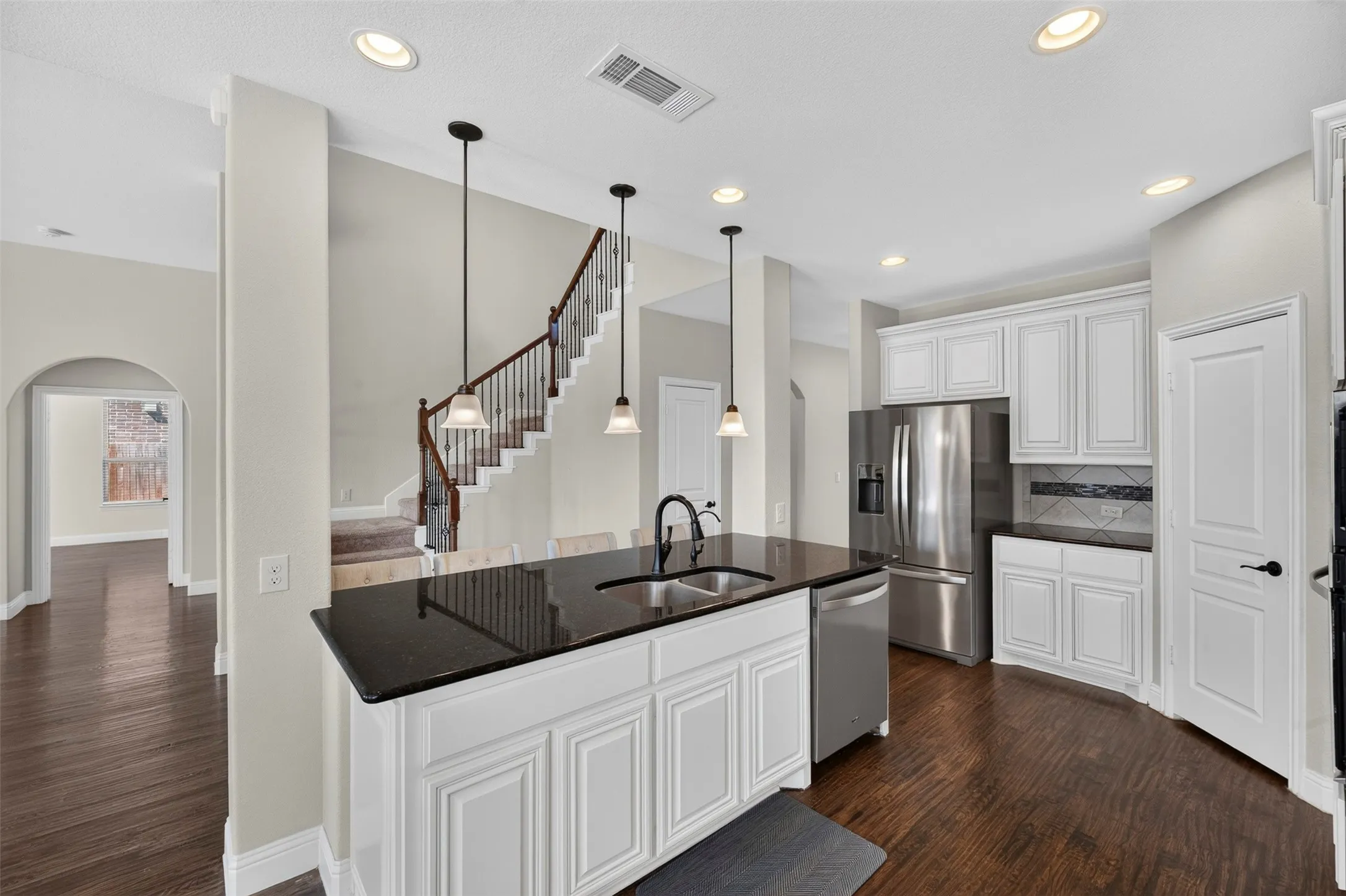 Kitchen featuring white cabinetry, dark countertops, stainless steel appliances, and wood-finish flooring