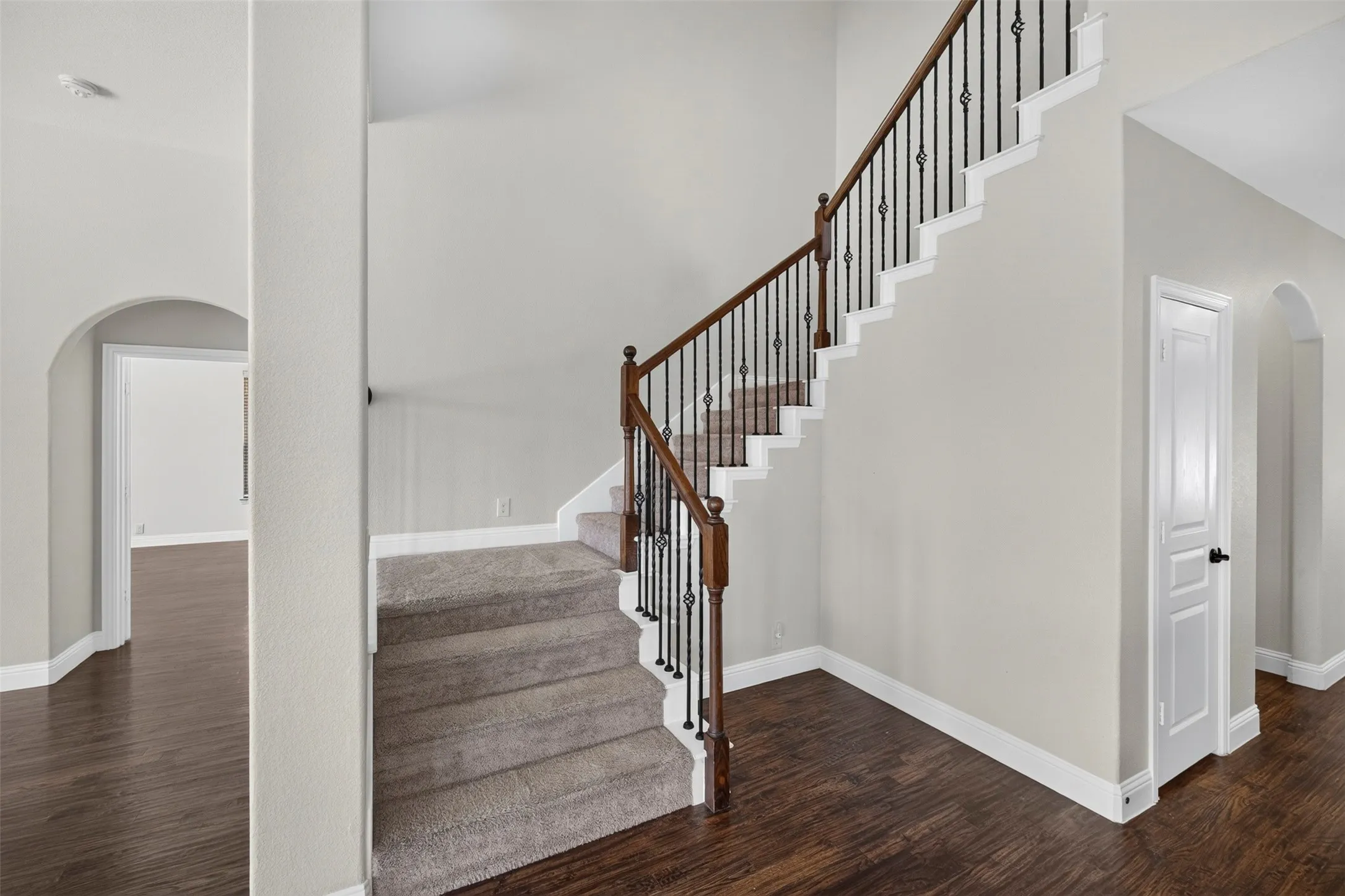 Staircase featuring wrought iron balusters and a wood handrail