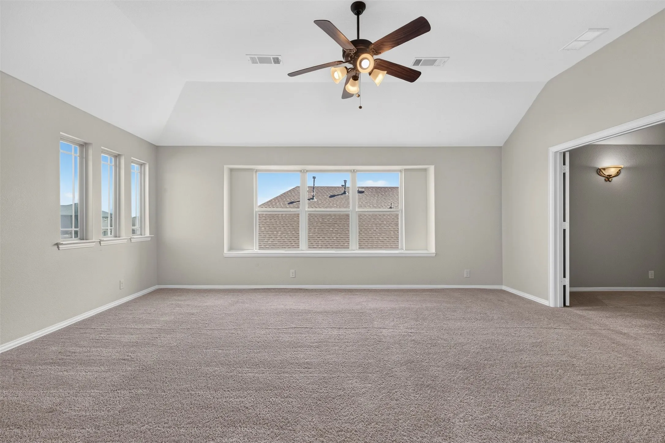 Tray ceiling, ceiling fan, multiple windows, and neutral carpet flooring
