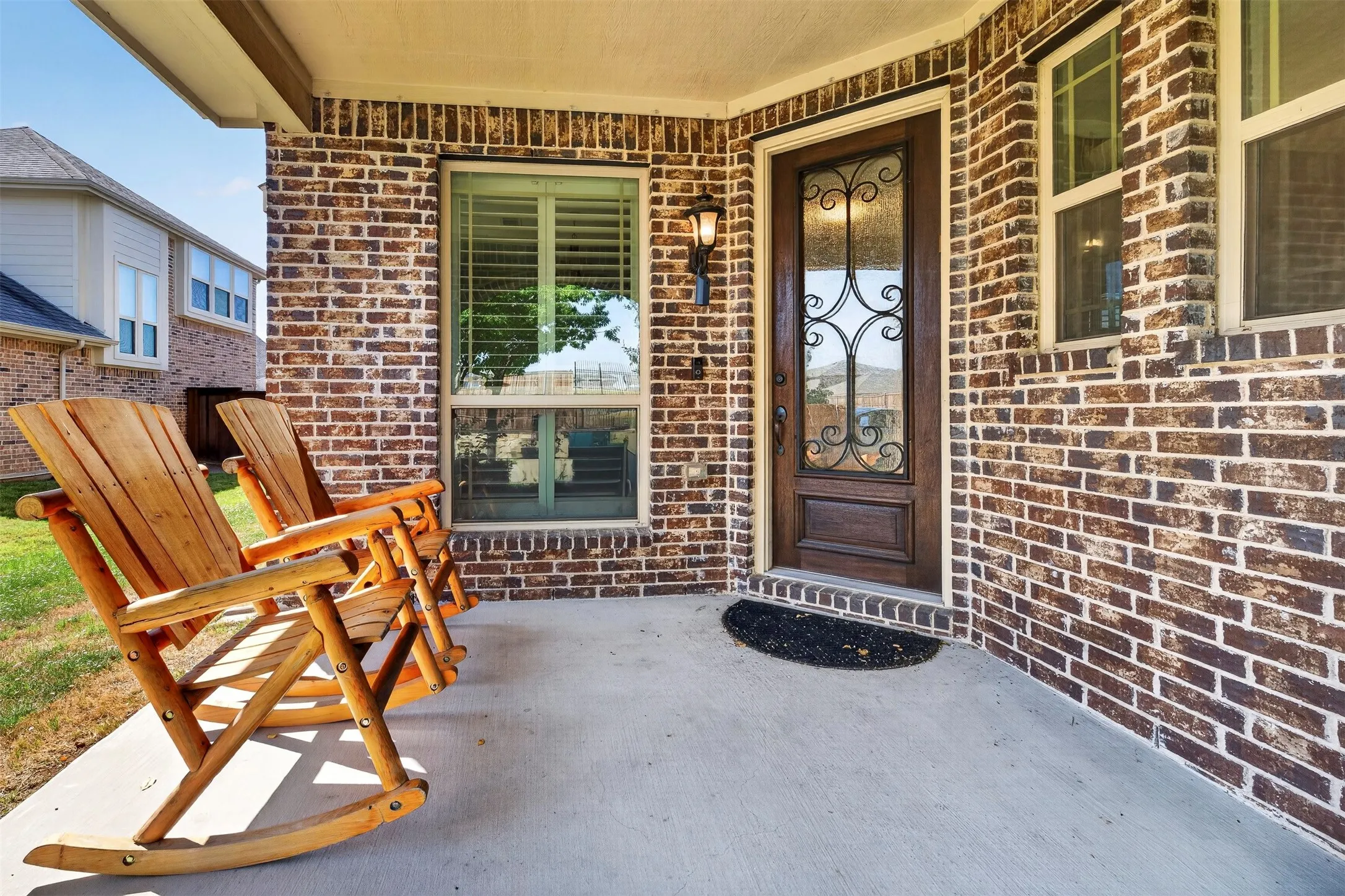 Brick exterior with covered porch featuring French doors, decorative sidelights, and concrete flooring