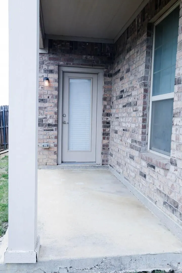 Covered patio with brick exterior and an outdoor light fixture