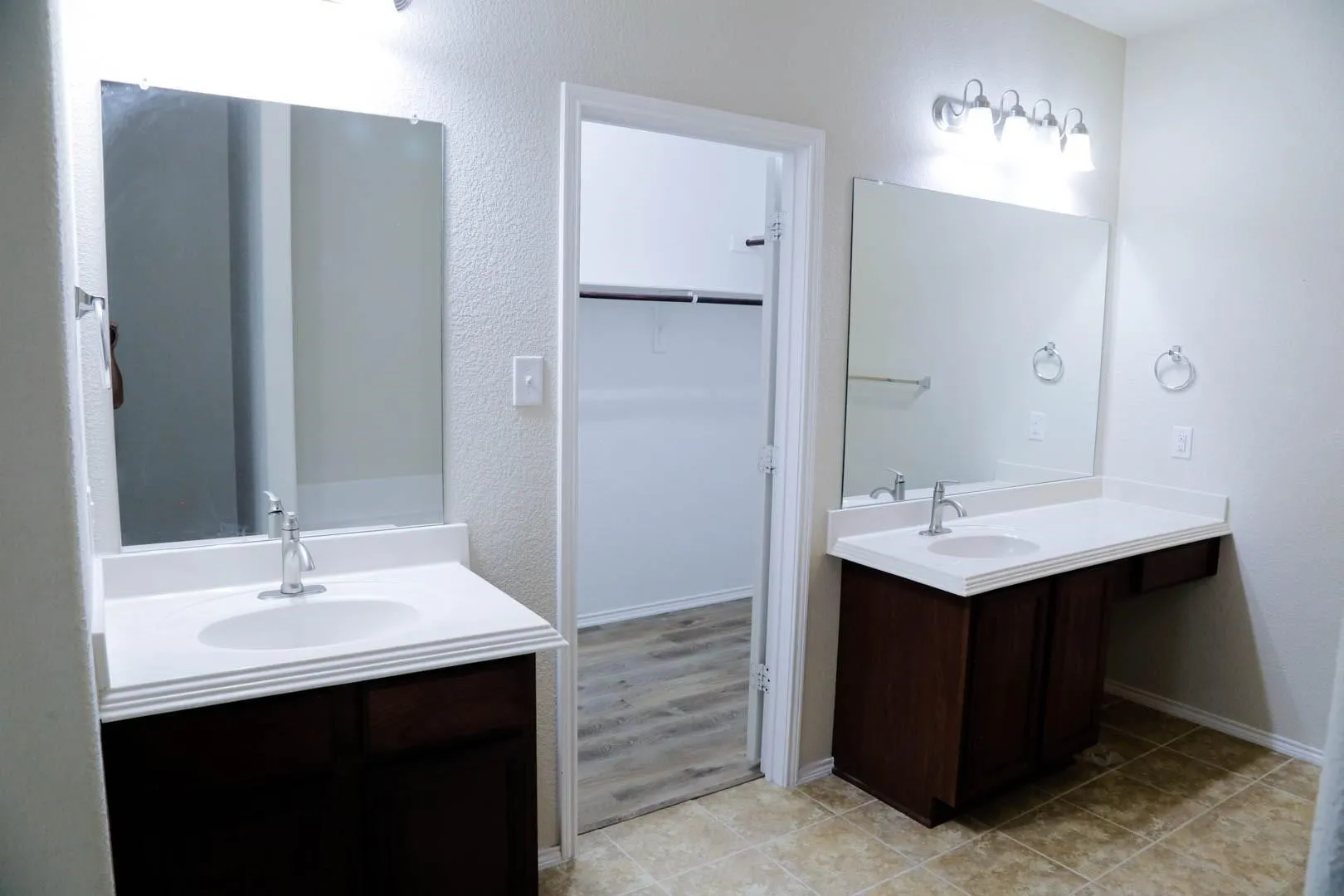 Dual vanity with integrated sinks, white countertops, dark wood-finish cabinetry, and overhead lighting fixtures