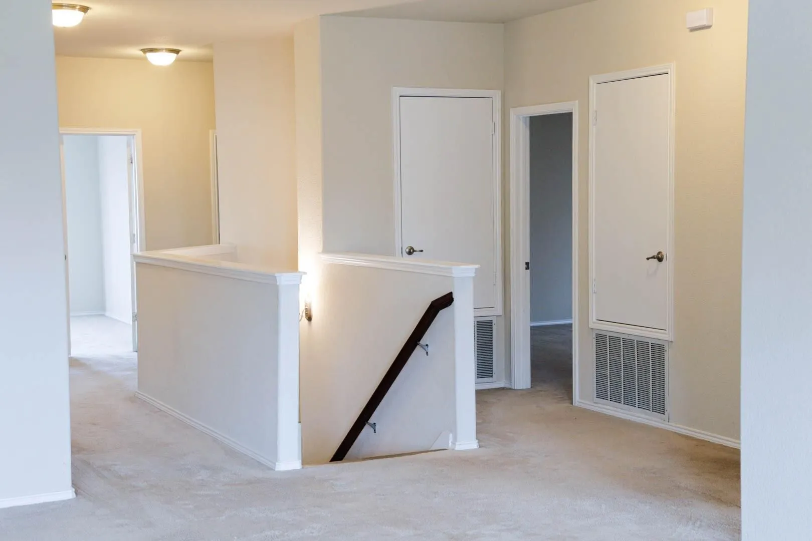 Carpeted upper landing with painted walls, multiple doorways, and recessed lighting