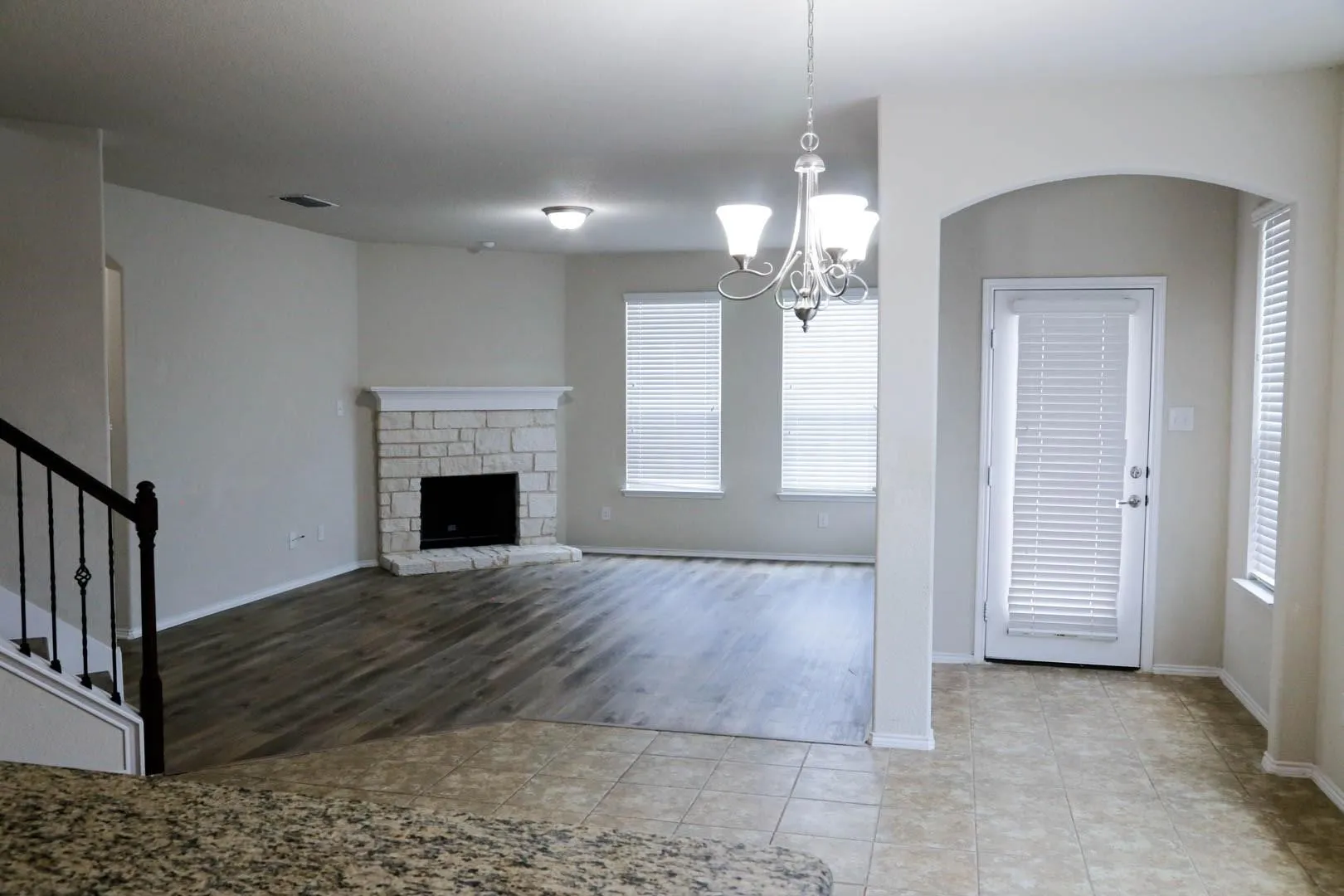 Spacious living area featuring a stone fireplace, wood-finish flooring, and multiple windows