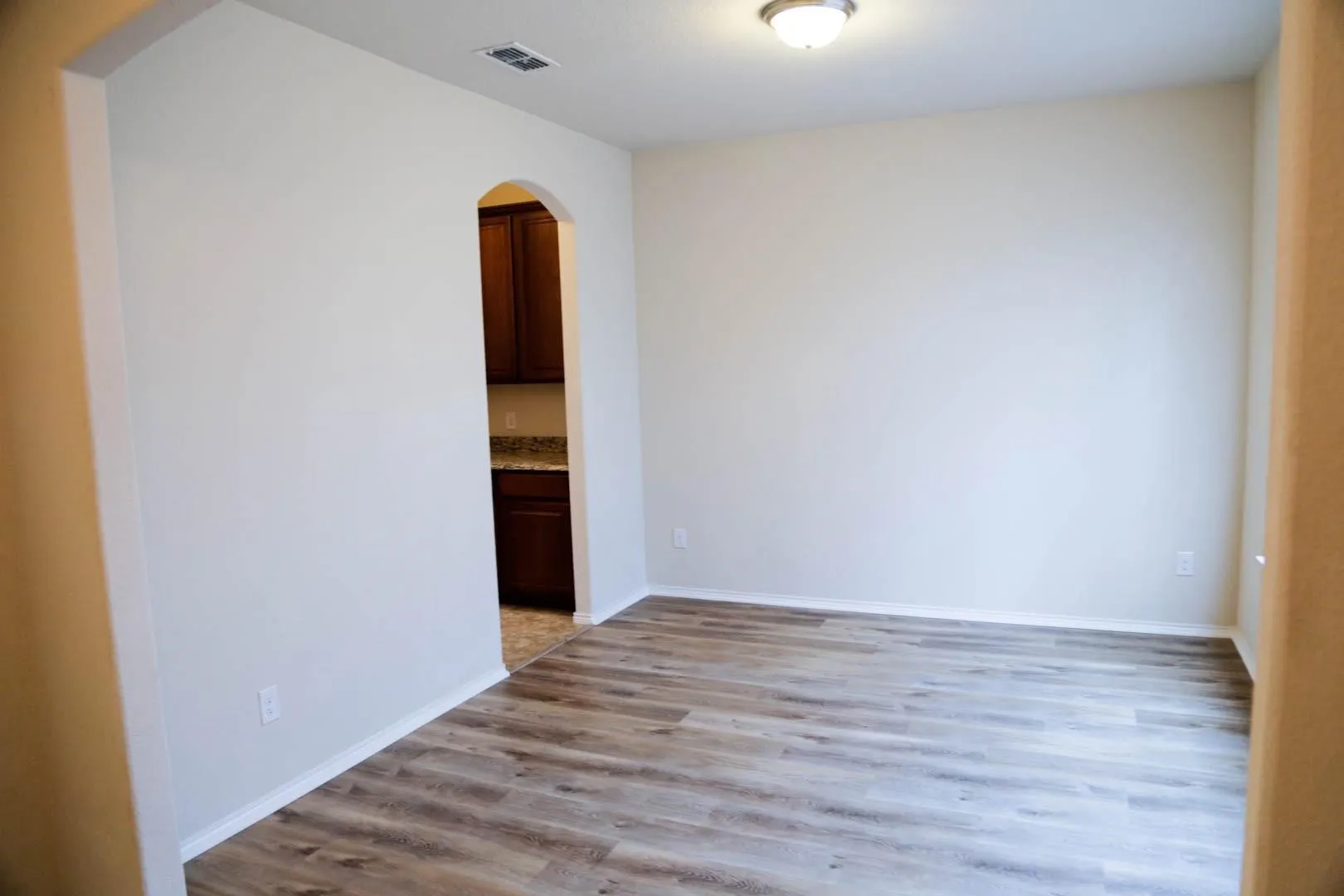 Wood-finish flooring with light-toned walls and an arched doorway