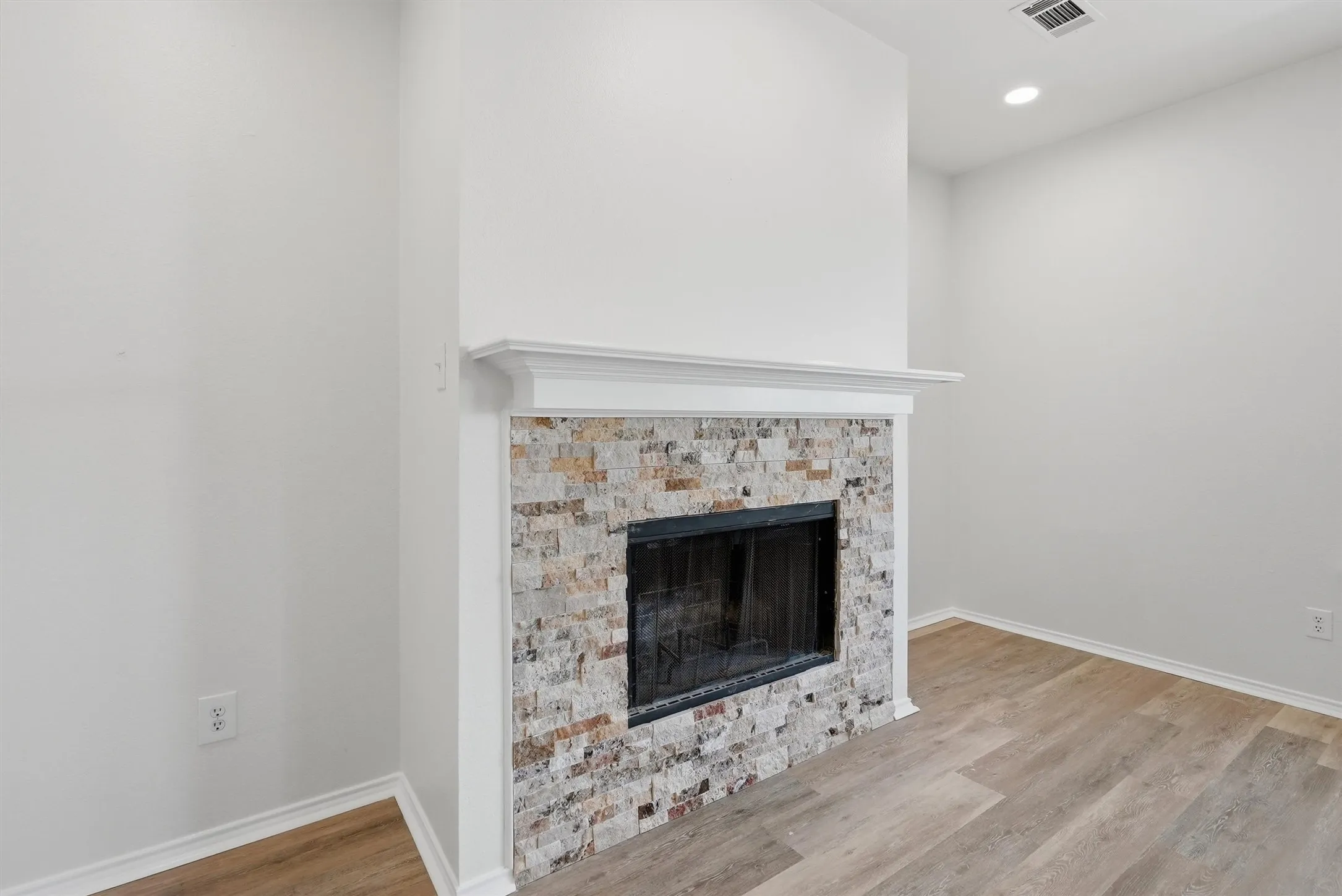 Fireplace featuring a stone tile surround, a classic white mantel, and a black firebox