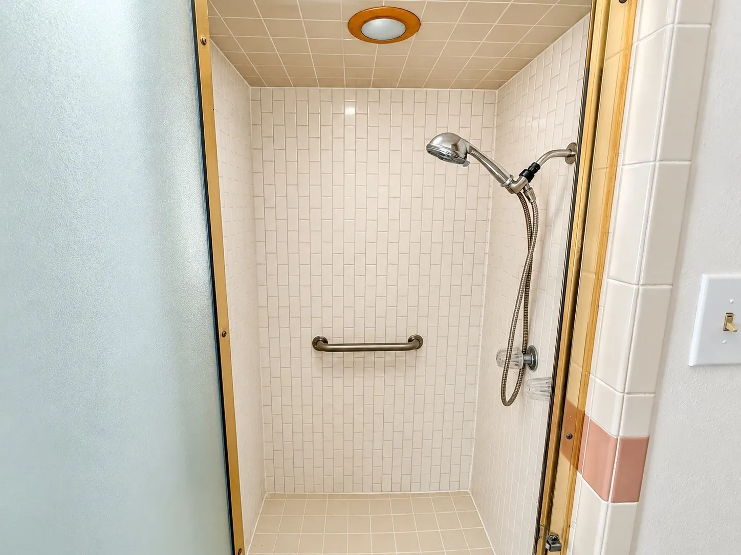 Walk-in shower with mosaic tile walls, tiled ceiling, and a grab bar
