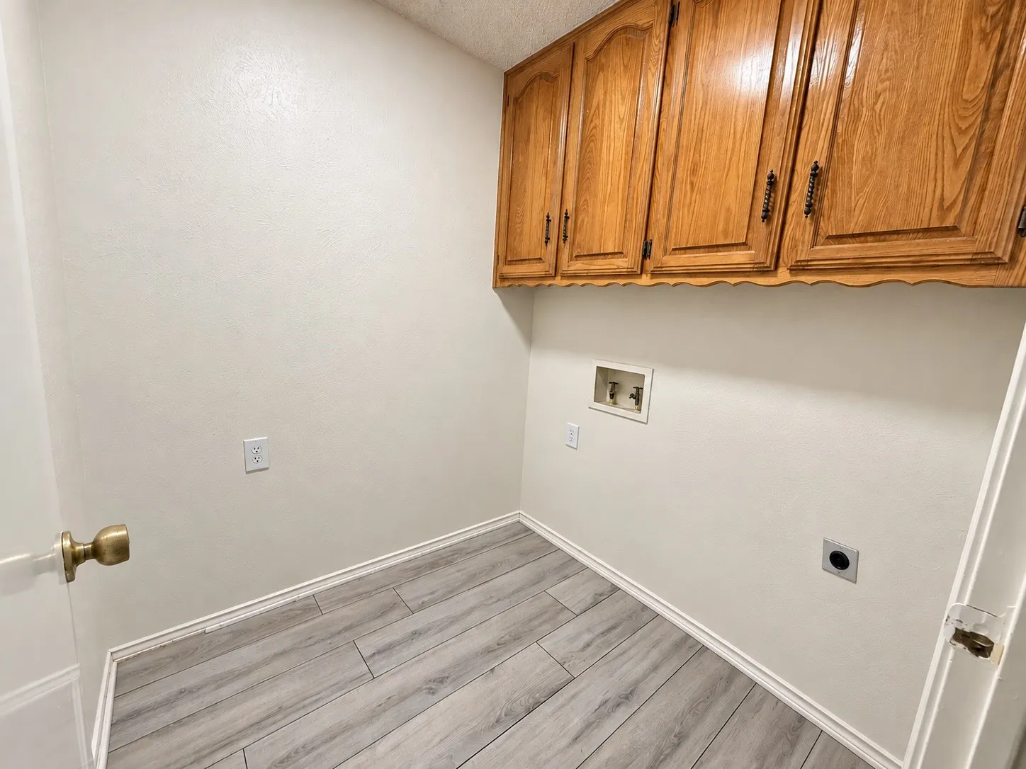 Wood-finish flooring, overhead cabinetry, and laundry hookups