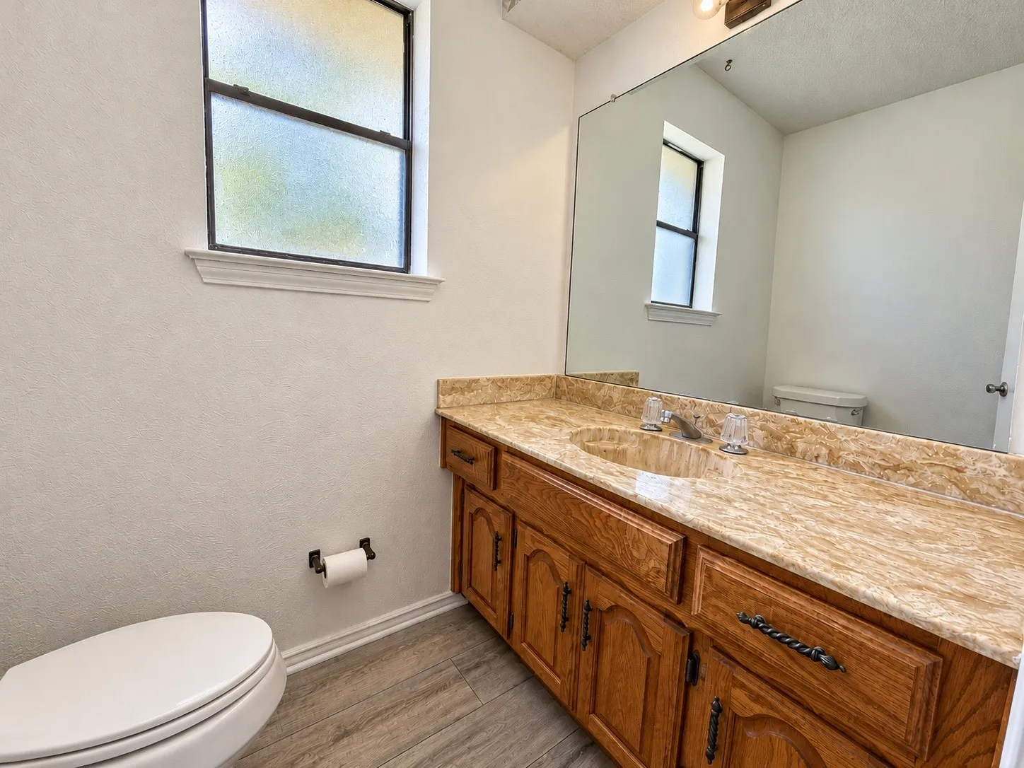 Dual sink vanity with wood cabinetry, light-toned countertop, and chrome fixtures