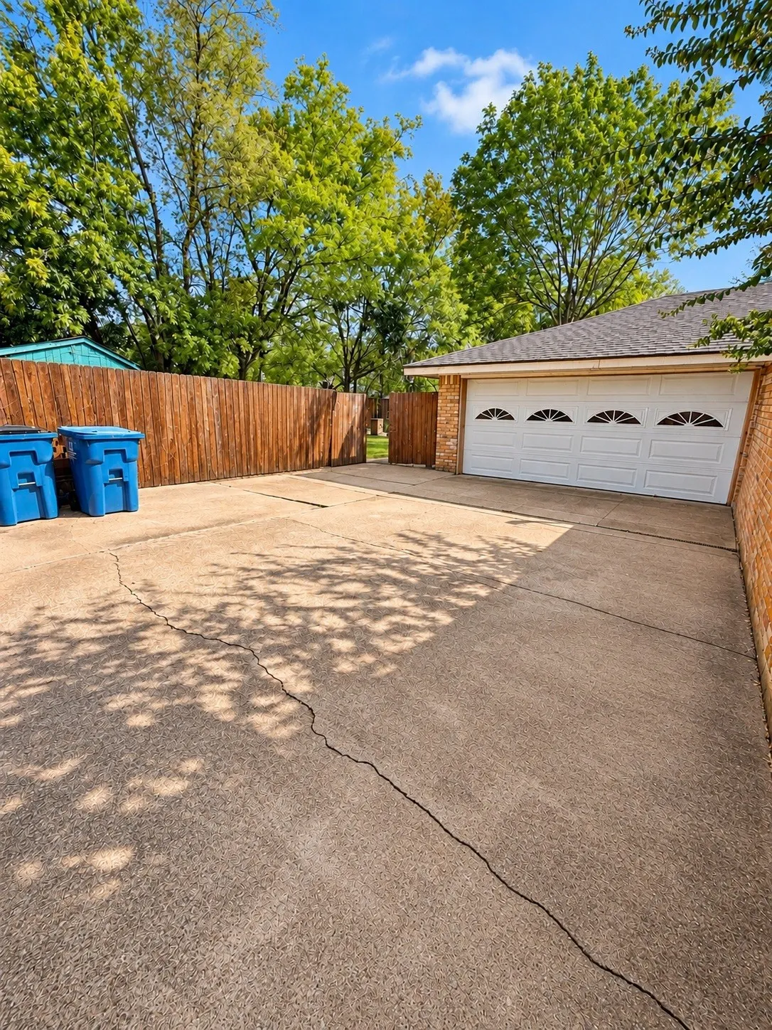 Concrete driveway, wood privacy fence, brick exterior, four-car garage door