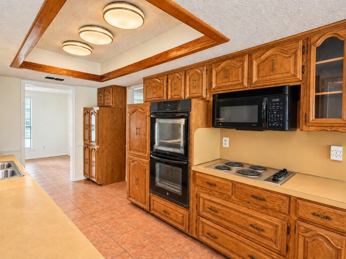 Kitchen featuring wood cabinetry, integrated double ovens, an electric cooktop, a built-in microwave, and tile flooring