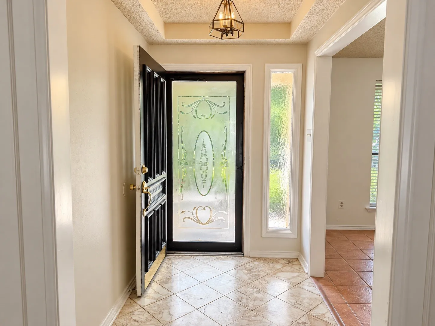 Entryway featuring a decorative glass front door with a sidelight, tiled flooring, and a coffered ceiling with a mounted light fixture
