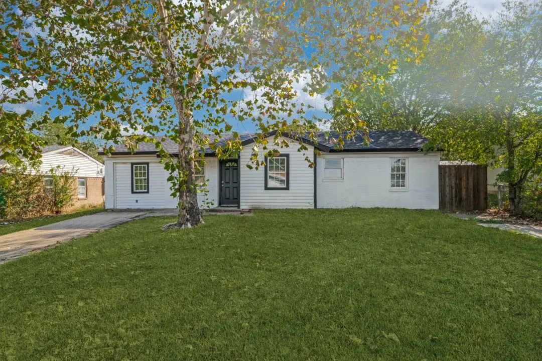 White exterior with black trim, a dark entry door, and a paved driveway
