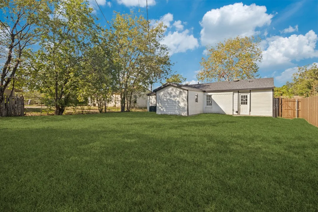 Expansive lawn with mature trees and a wood privacy fence
