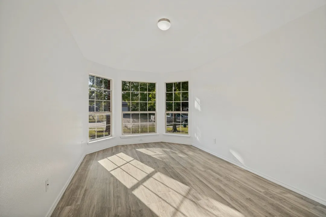 Bay window with multiple panes, wood-finish flooring, and a flush-mount ceiling light