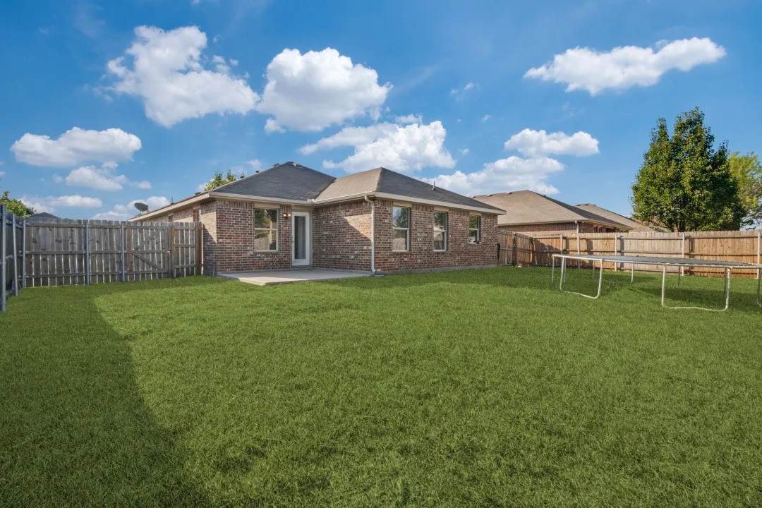 Expansive green lawn, brick exterior, paved patio, and privacy fencing