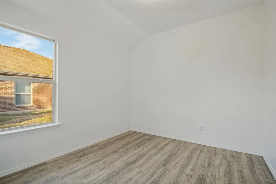 Neutral paint palette with wood-finish flooring, a white window frame, and an angled ceiling