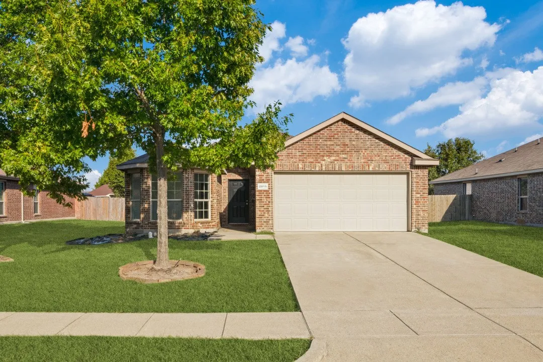 Brick exterior, attached garage, concrete driveway, front yard, and sidewalk