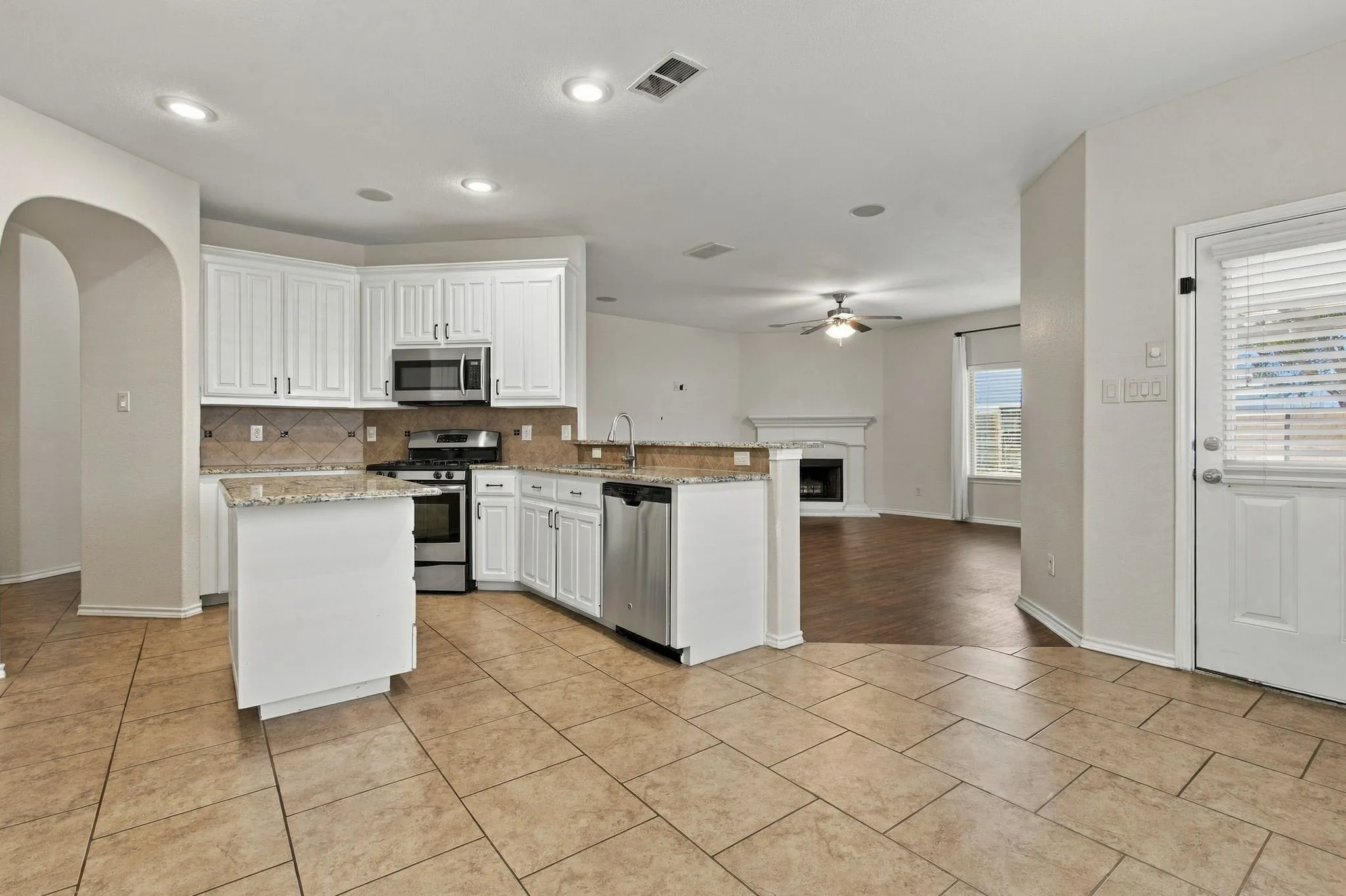 Kitchen featuring white cabinetry, stainless steel appliances, a tiled backsplash, and stone countertops