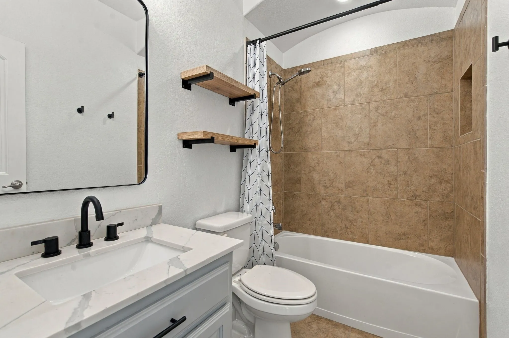Bathroom featuring a white vanity with an integrated rectangular sink, a stone-finish countertop, and matte black fixtures