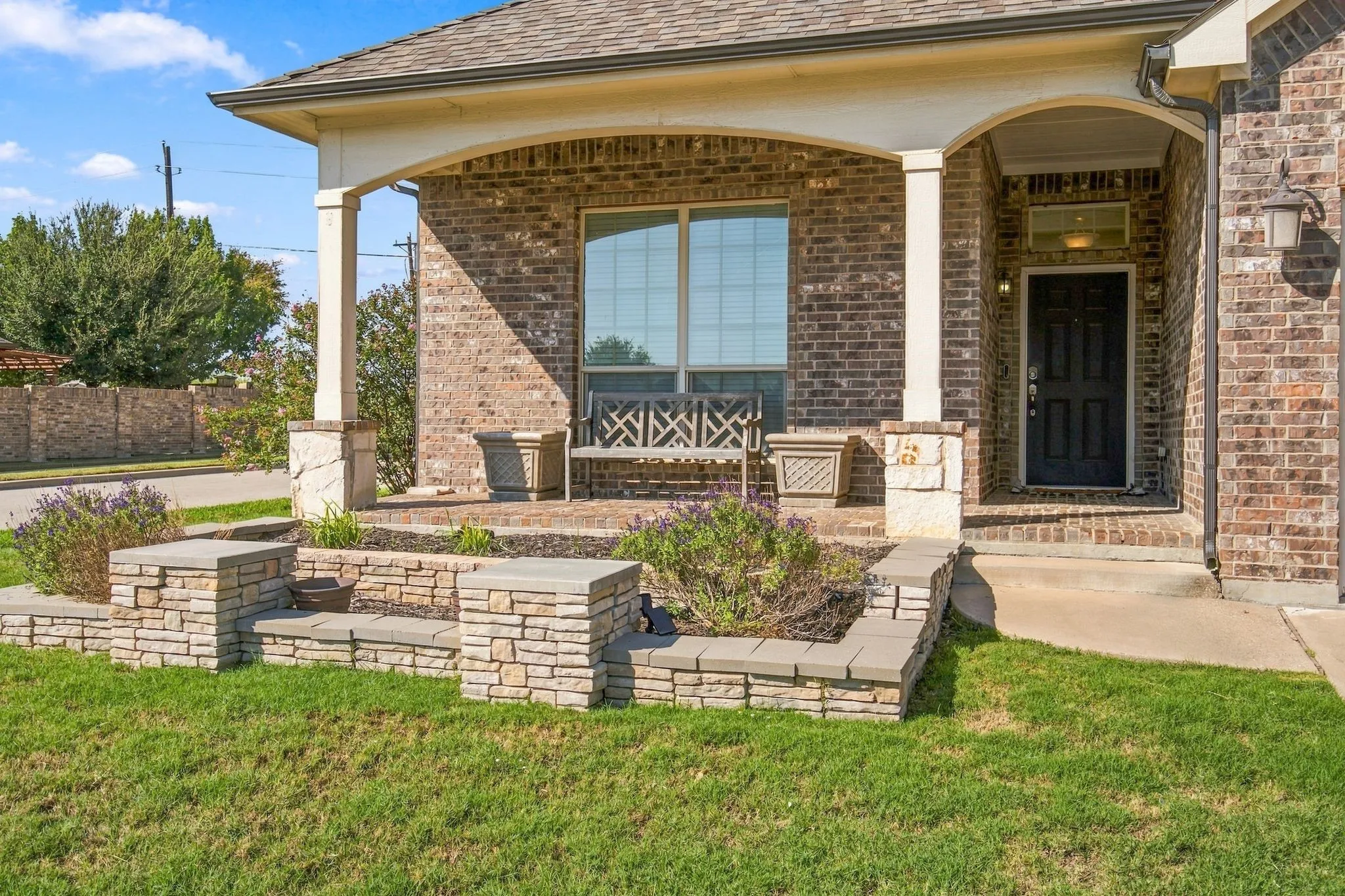 Brick facade with a covered entry, arched porch supports, and a dark paneled door