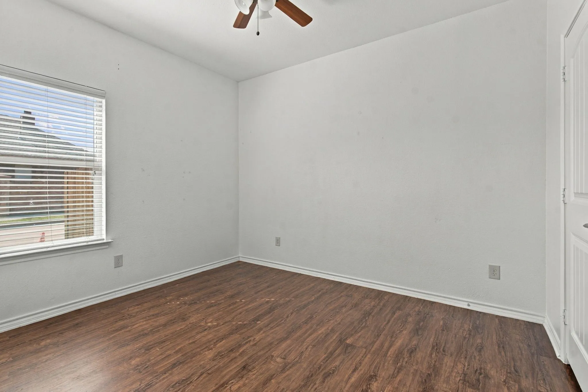 Wood-finish flooring, white walls, window with blinds, and ceiling fan