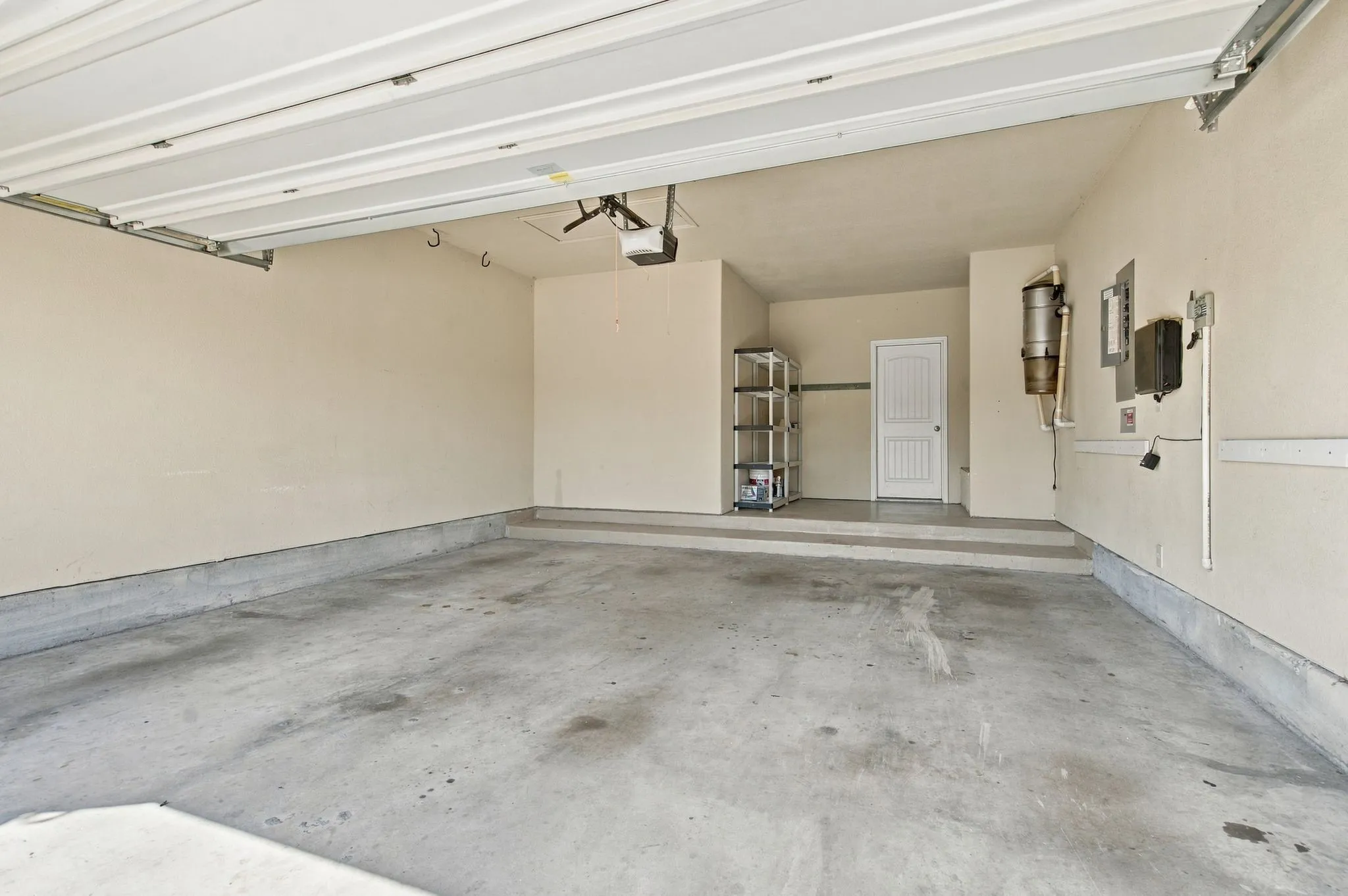 Spacious garage with concrete flooring, automatic garage door opener, and a built-in central vacuum system