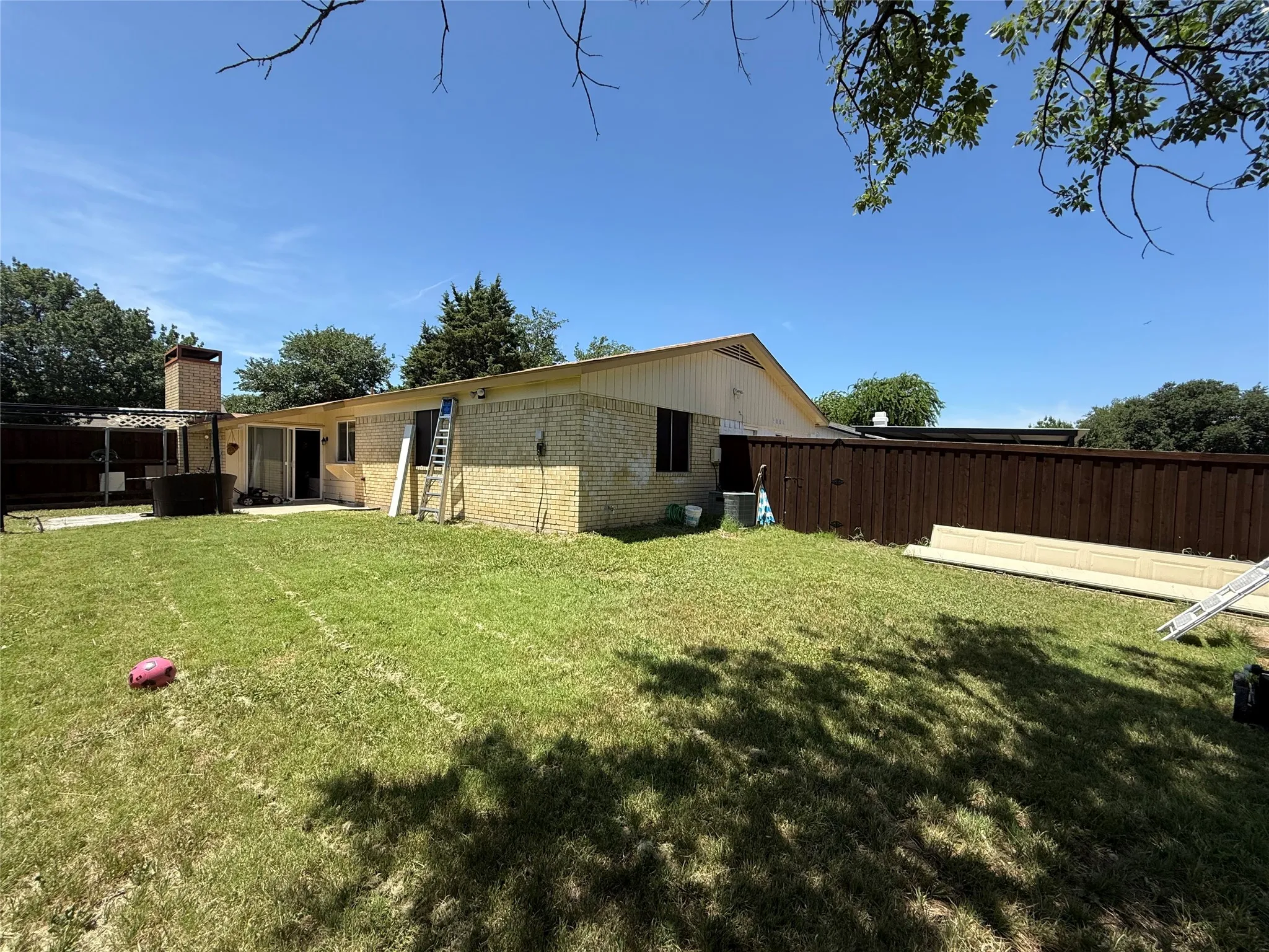 Expansive backyard featuring a privacy fence, brick exterior, and a built-in outdoor structure