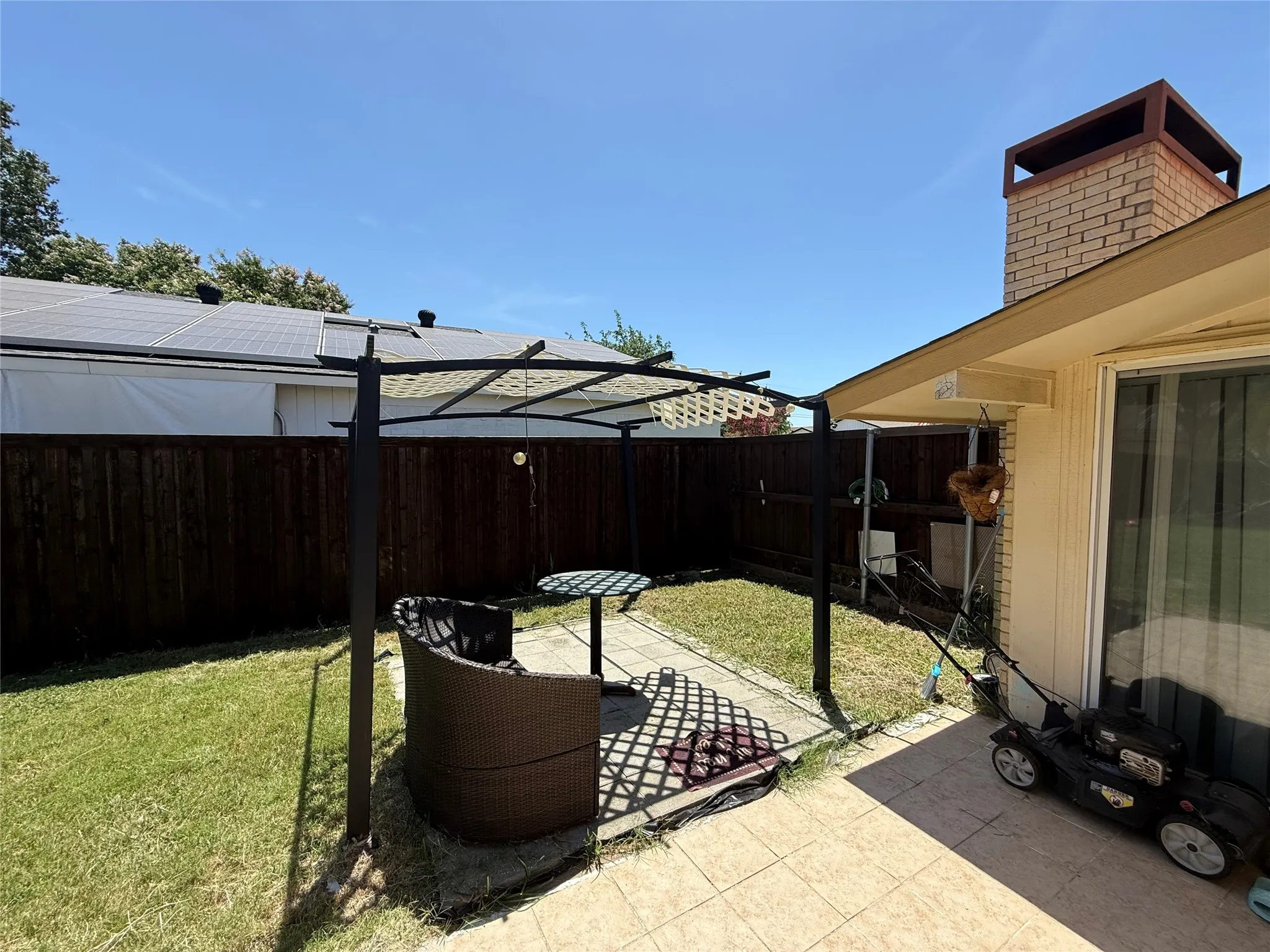 Private backyard with wood fencing, a brick chimney, and an attached covered patio