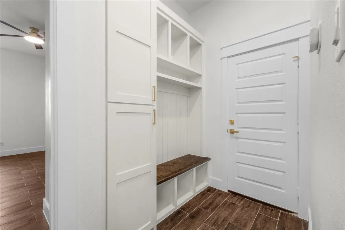 Built-in storage cabinetry with gold-tone hardware, a dedicated bench, and integrated shelving