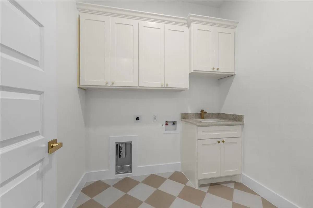 White shaker cabinetry, stone-finish countertop, undermount sink, brass finish hardware, and checkerboard floor tiling