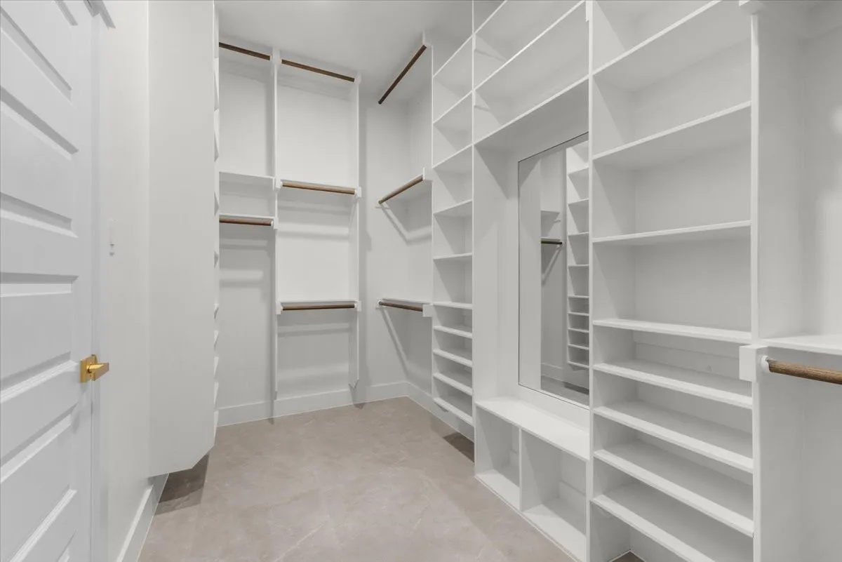 Extensive custom closet system featuring white shelving, integrated mirror, multiple hanging rods, and ample storage compartments