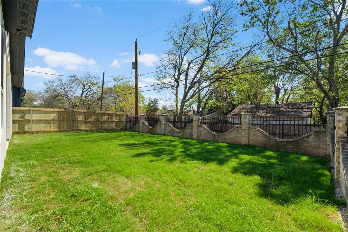 Manicured lawn with a wood privacy fence and a decorative stone and iron fence