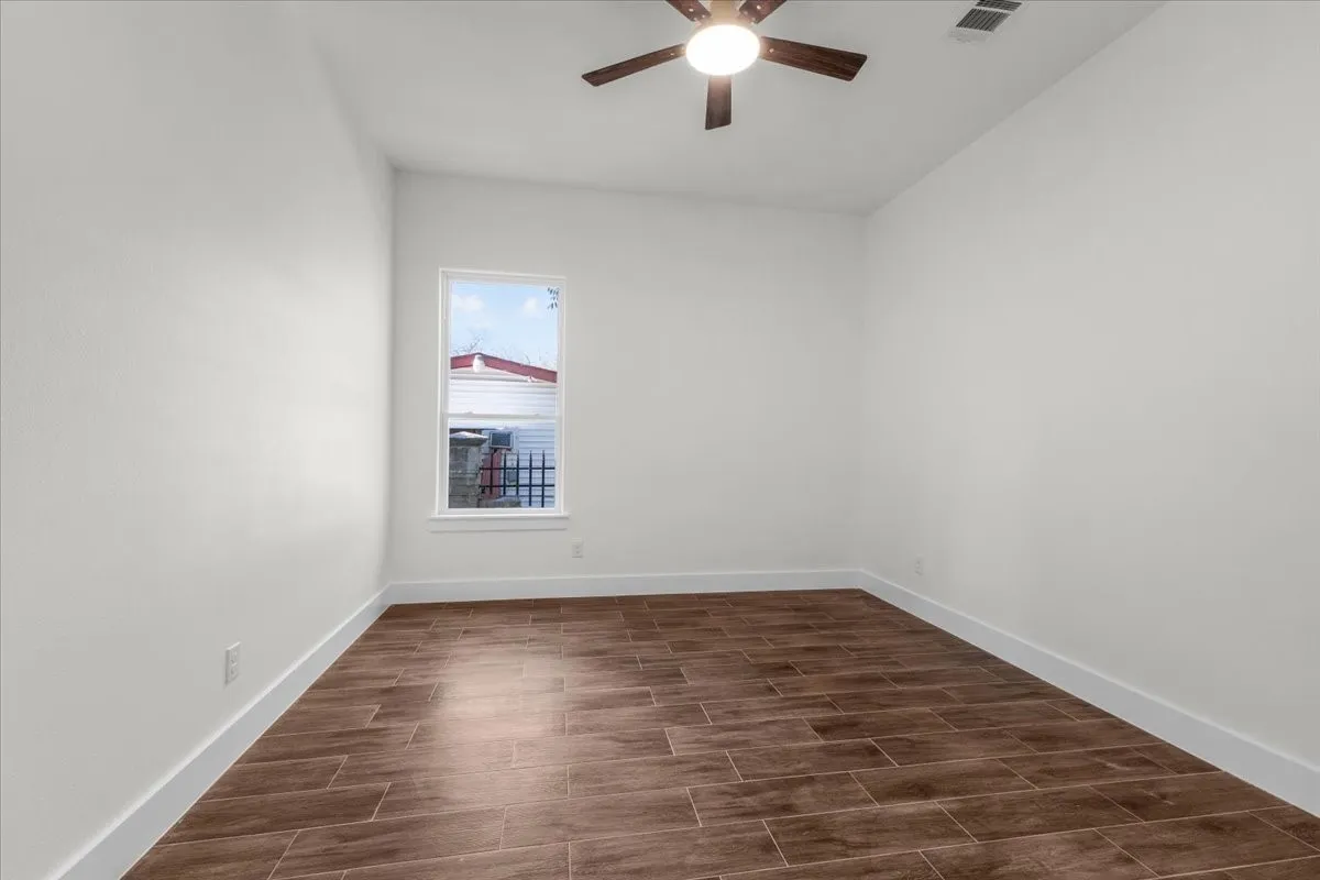 Wood-finish flooring, white walls, and a ceiling fan with integrated lighting