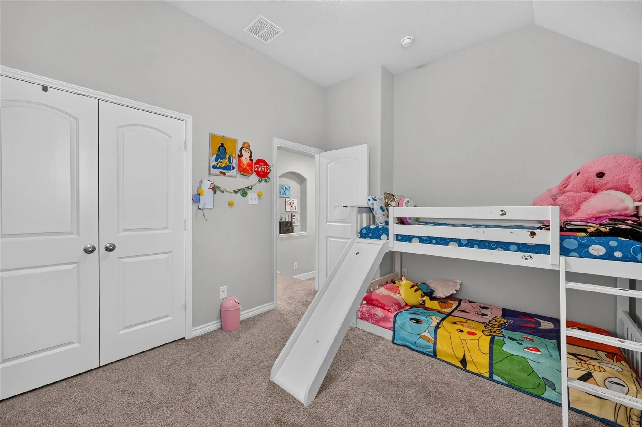 Carpeted flooring, vaulted ceiling, white trim, archway entry, and double-door closet