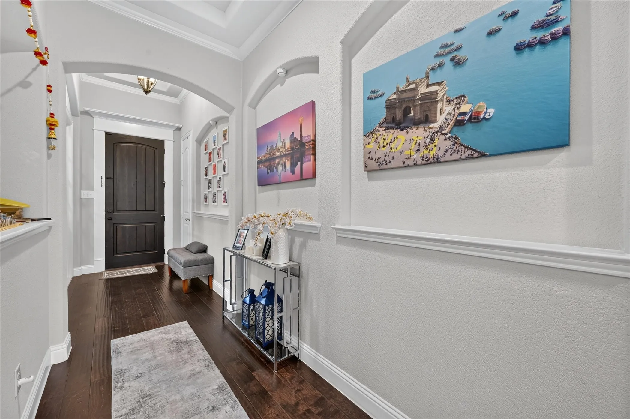 Dark wood-finish flooring with white baseboards, arched entryways, and crown molding