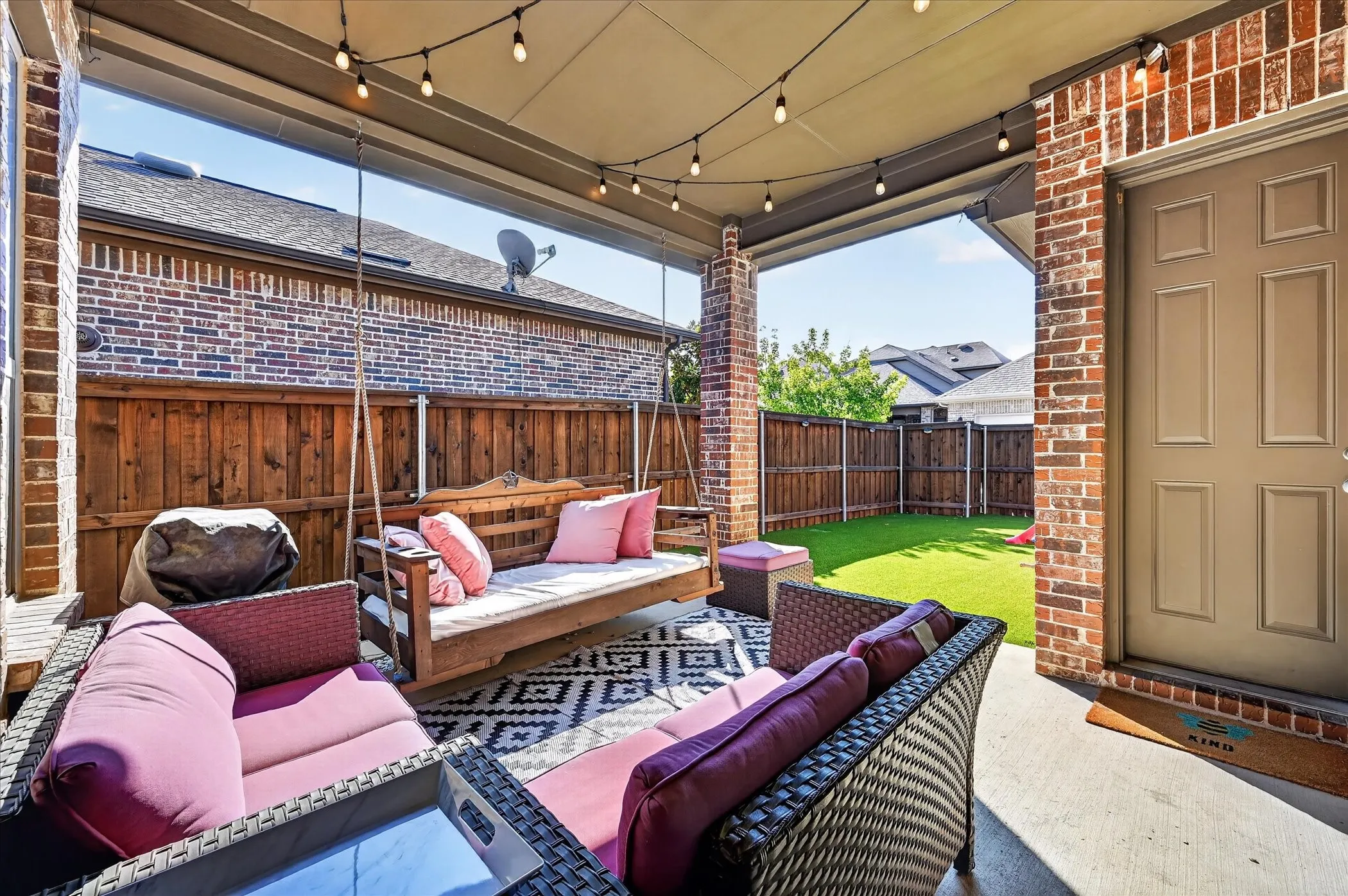 Covered patio with string lighting, concrete flooring, and brick columns