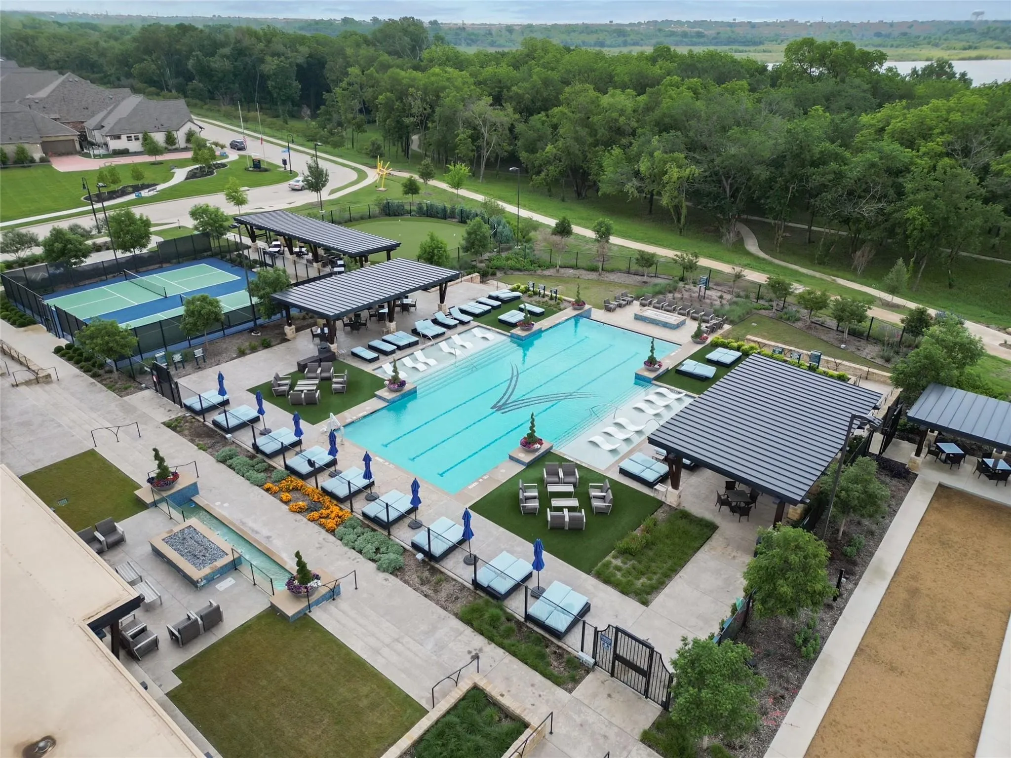 Resort-style amenities featuring a large outdoor pool, tennis court, bocce ball court, covered outdoor lounge areas, and a linear fire feature