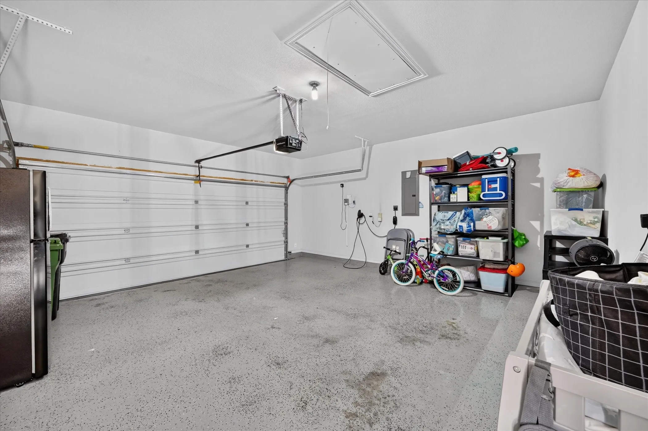 Attached garage featuring a white overhead door, finished walls, and an access panel