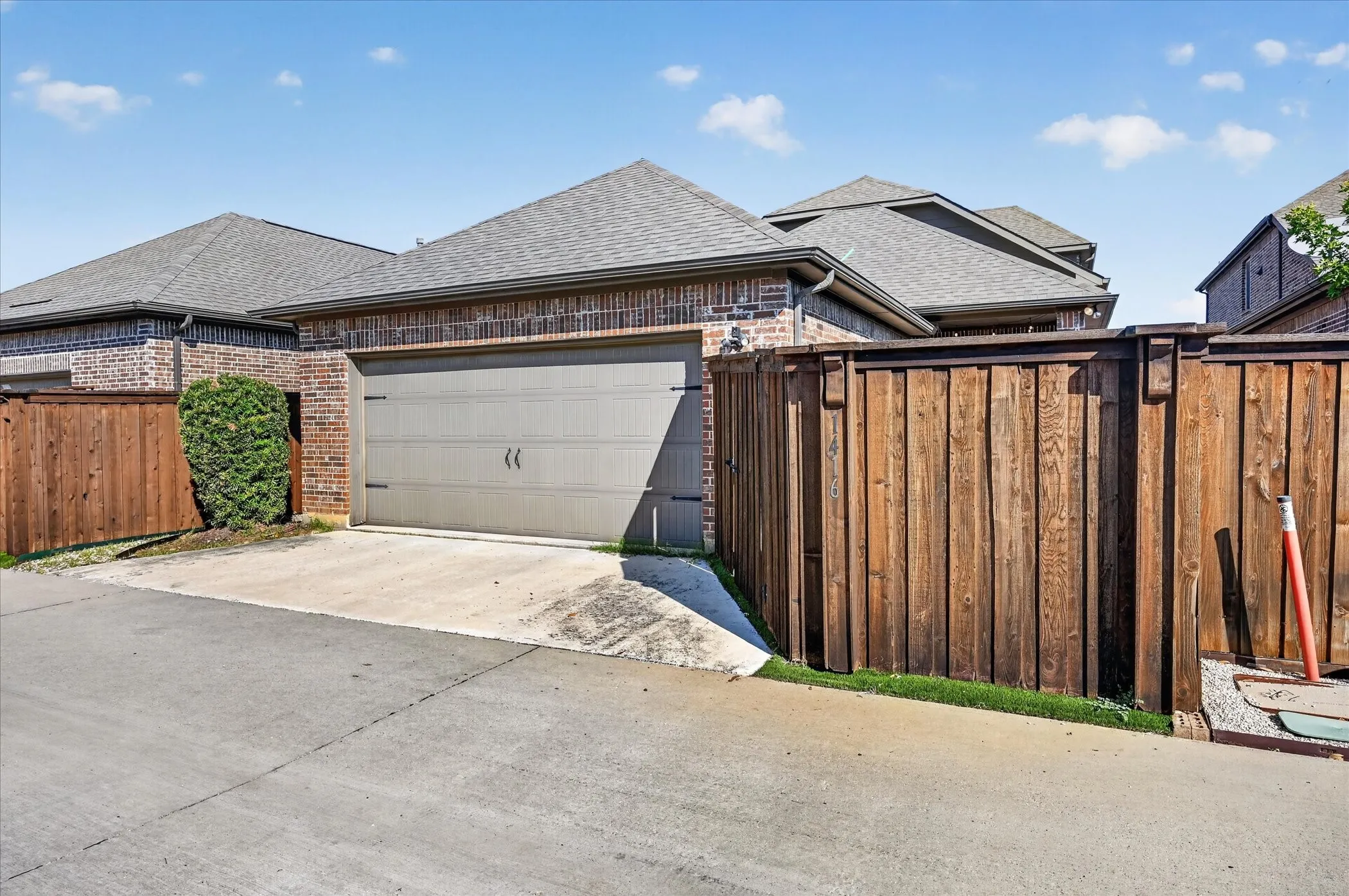 Brick exterior with a two-car garage and wood privacy fencing