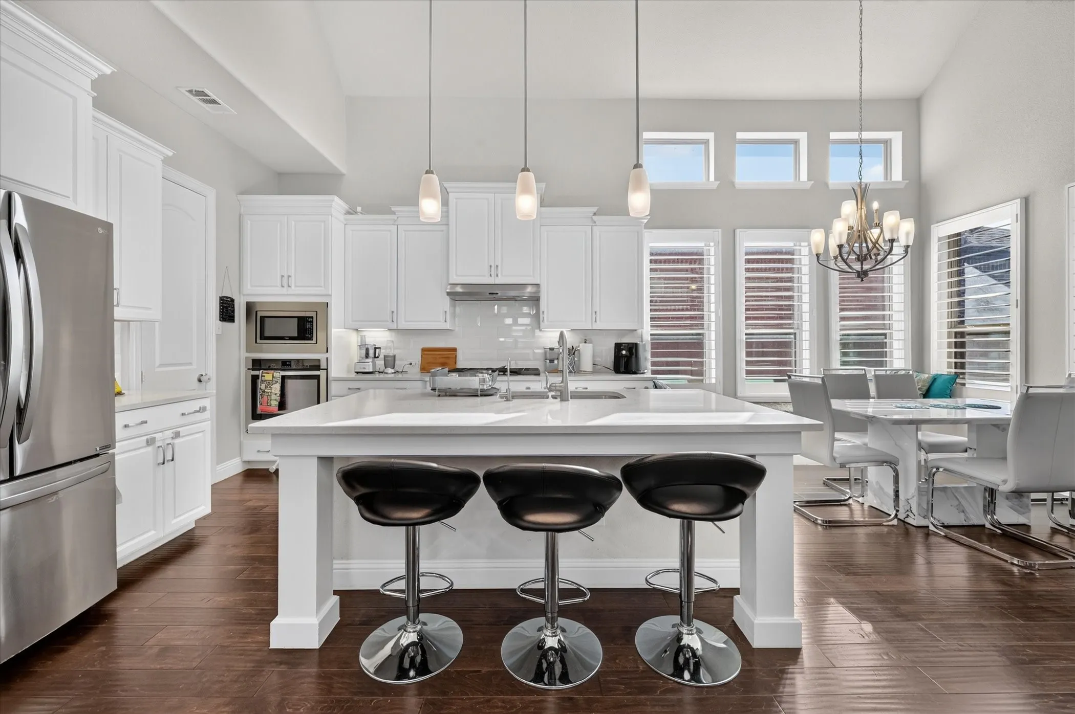 Spacious kitchen featuring white cabinetry, stainless steel appliances, a large center island, and wood-finish flooring
