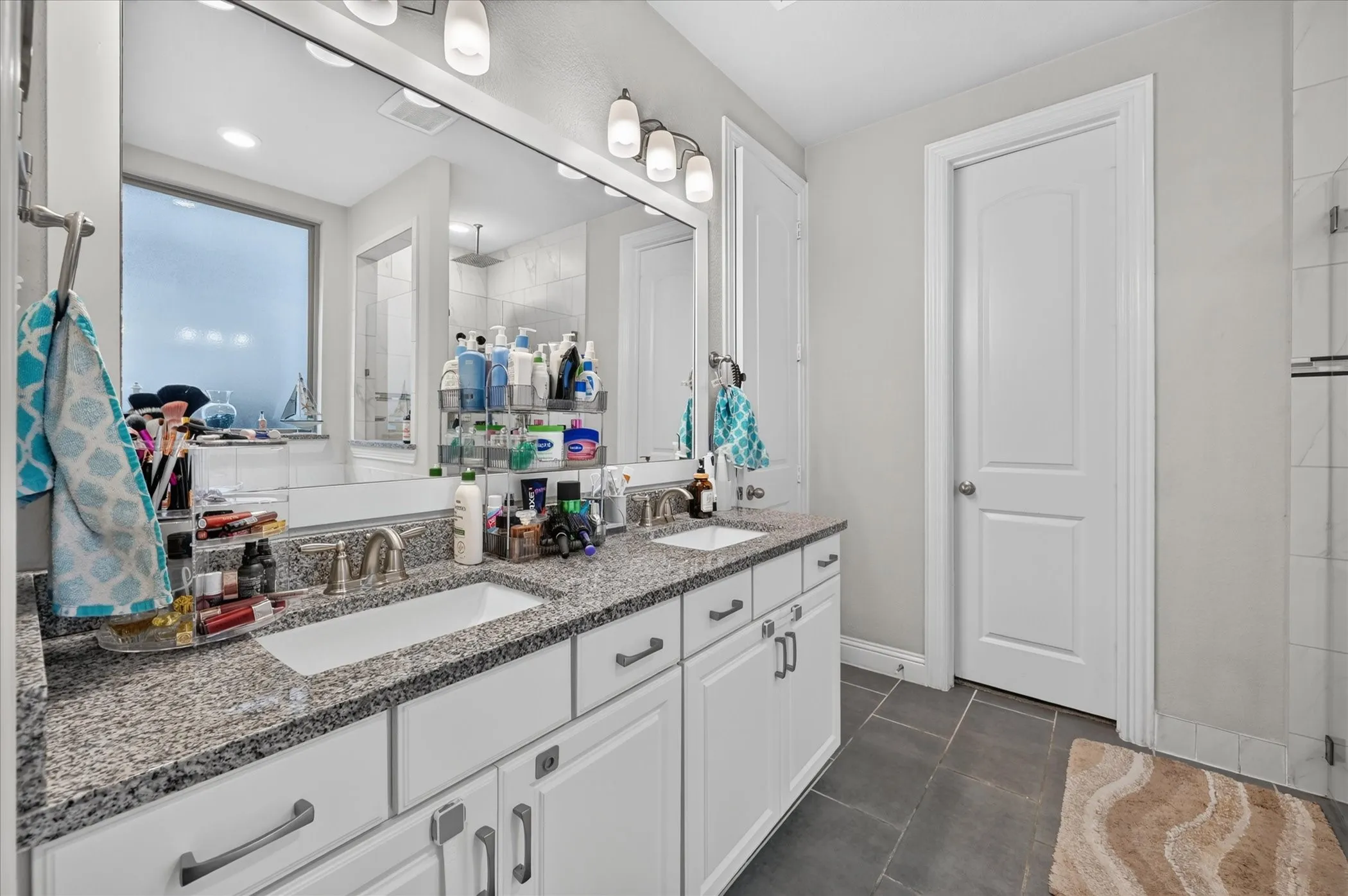 Dual vanity with granite countertops, undermount sinks, and white cabinetry