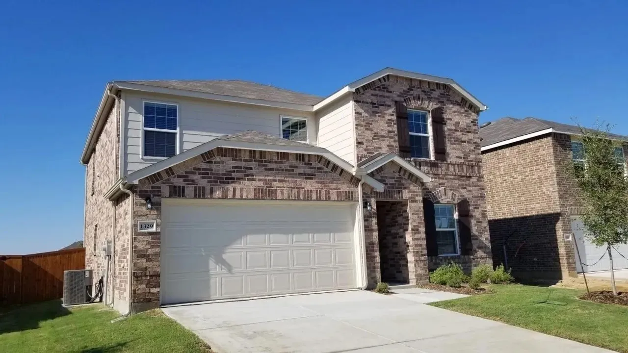 Two-story exterior with brick and siding facade, attached two-car garage, and concrete driveway