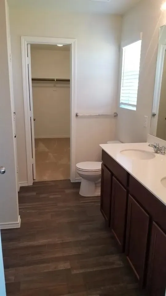 Master Bathroom with wood-finish flooring, a dual-sink vanity, and a window with blinds